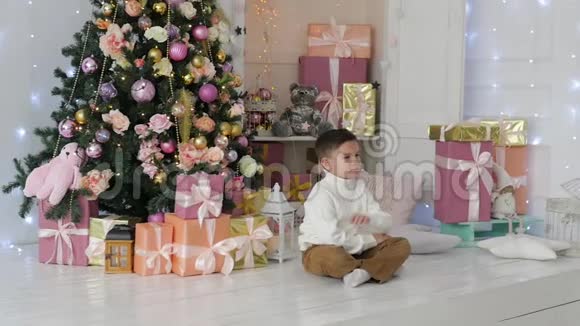 小男孩坐在新年工作室里的圣诞室内背景上视频的预览图