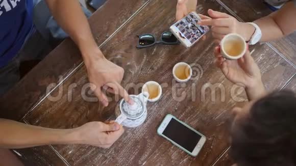 年轻的混合种族朋友在咖啡厅喝中国茶并使用手机小玩意4K视频的预览图