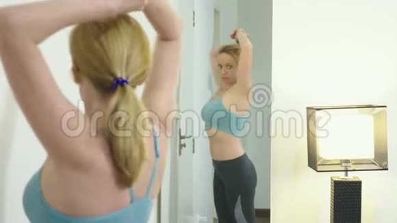 超重和减肥的概念穿着运动服的女人在卧室里照镜子视频的预览图