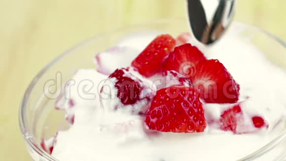 男人用勺子在透明的杯子里吃健康的草莓配上白色酸奶健康水果的概念视频的预览图