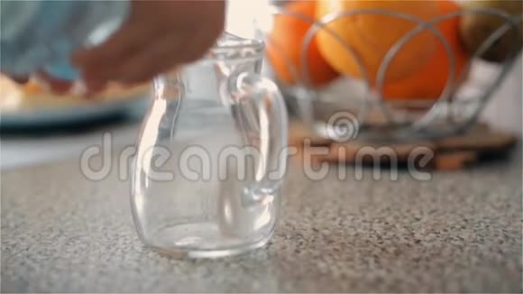 孩子慢慢地从塑料瓶里倒进一壶干净的饮用水里视频的预览图