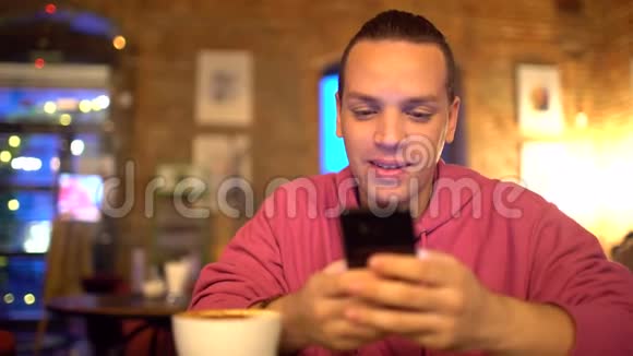 迷人的西班牙裔男人一个商人一个学生或一个创业公司用手机带着迷人的微笑人发短信视频的预览图
