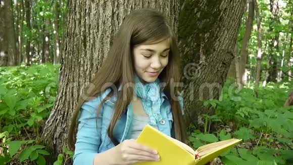 一幅可爱的十几岁女孩在森林里看书翻页的画视频的预览图