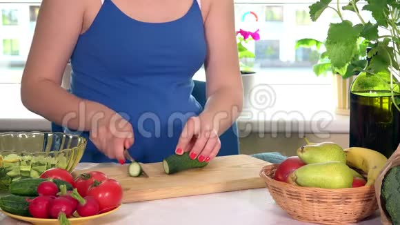 孕妇的大肚子和厨房桌上切黄瓜的手视频的预览图