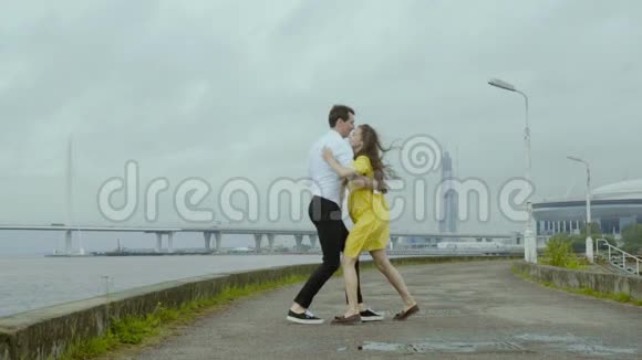 迷人的女孩和男孩有感情地跳舞一些复古的舞蹈在一个码头的雨水池视频的预览图