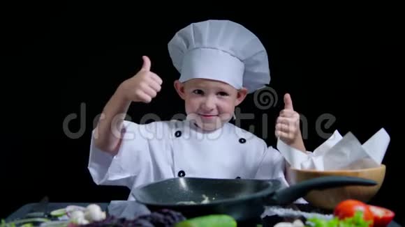 快乐的男孩正在跳舞做饭时竖起大拇指他穿着厨师服和帽子视频的预览图