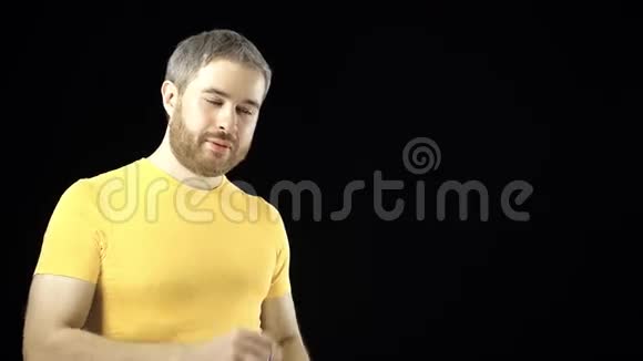 穿黄色t恤的灰发男子从小弹胶瓶中饮水黑色背景4K视频视频的预览图