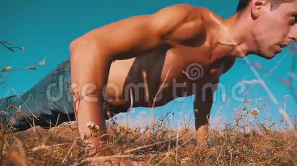 裸露躯干的年轻运动员在大自然中做俯卧撑慢动作视频的预览图
