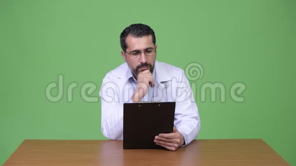 英俊的波斯胡子男人医生读着写字板思考着视频的预览图