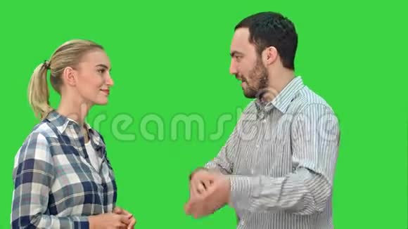 英俊的男人和迷人的年轻女人在绿色屏幕上交谈和微笑Chroma键视频的预览图