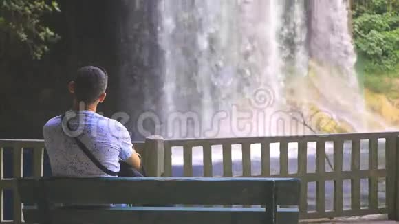 孤独的人坐在公园的长椅上瀑布视频的预览图