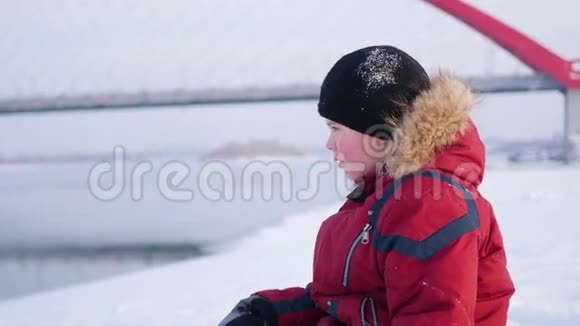 孩子坐在岸边望向远方冬季景观视频的预览图