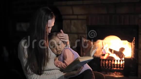 女人和女儿坐在壁炉前看书视频的预览图