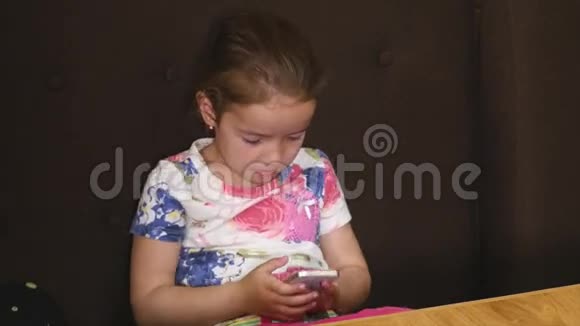 小女孩在咖啡馆里晒黑在游戏中玩智能手机视频的预览图