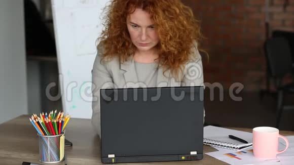 穿着红头发的女人在办公室工作视频的预览图