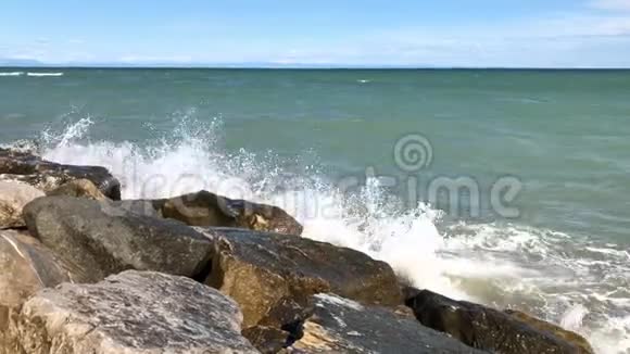 阳光明媚的一天海浪在石岸飞溅视频的预览图