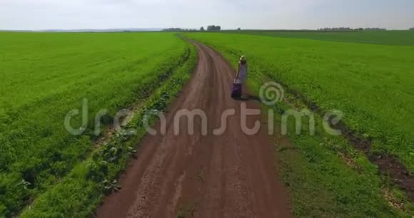 一个穿着连衣裙和帽子的女孩走过一片绿色的草地视频的预览图