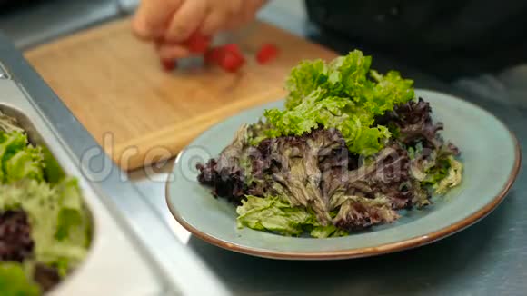 厨师在餐厅厨房里把西红柿放在生菜叶子上一步一步地做沙拉视频的预览图