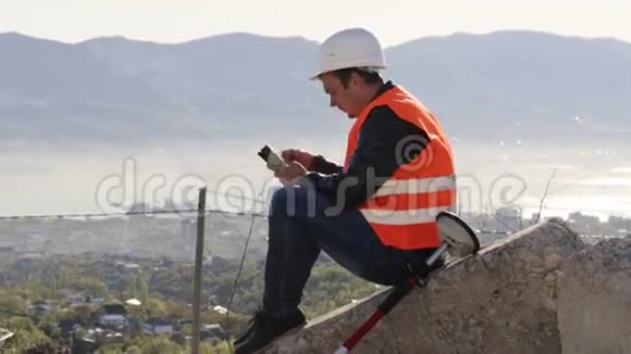 穿背心和头盔的白人工人坐在混凝土板上视频的预览图