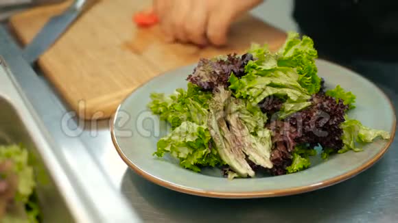 厨师在餐厅厨房里把西红柿放在生菜叶子上一步一步地做沙拉视频的预览图