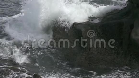 热带海洋的海岸在阳光明媚的日子里海浪在海岸上用黑色的石头奔跑缓慢的运动视频的预览图