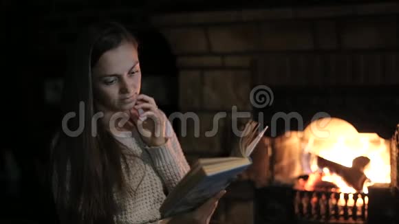 坐在壁炉前的年轻女子拿着书和狗视频的预览图