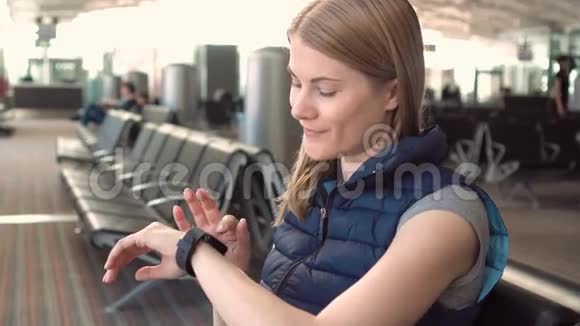 美丽迷人的年轻女子在机场使用智能手表给朋友发语音信息视频的预览图