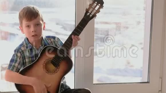 演奏乐器男孩弹吉他坐在窗台上唱歌视频的预览图