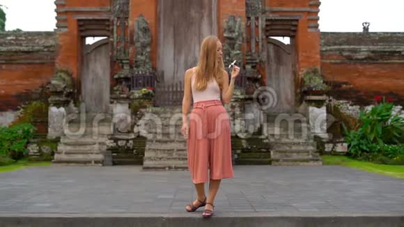 一名年轻女子在巴厘岛的塔曼阿云寺周围行走的慢镜头视频的预览图