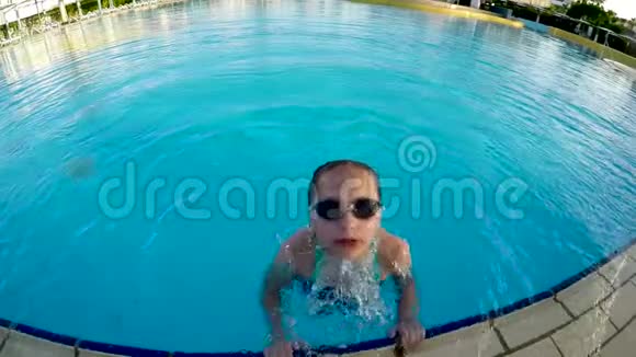 戴护目镜的小女孩在游泳池里玩耍视频的预览图