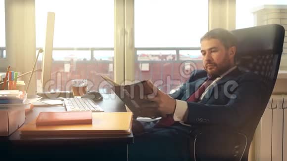 一个留胡子的年轻人在电脑上工作在办公室的笔记本上写字4K视频视频的预览图