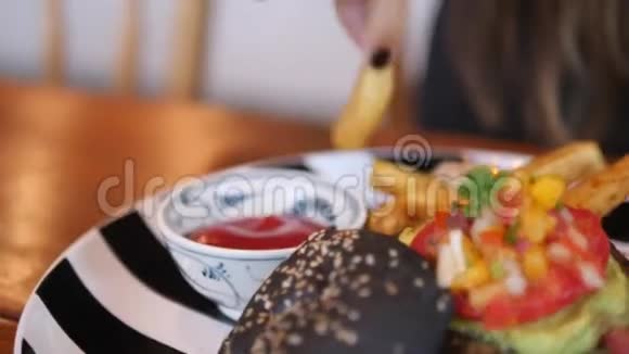 女人吃美味的法国薯条土豆片和健康的素食汉堡4快点视频的预览图