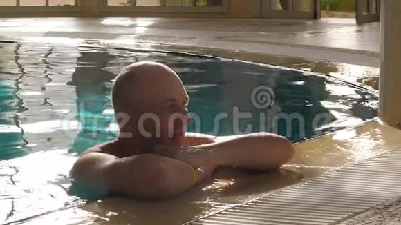 蓝水游泳池里休息的成年男子视频的预览图