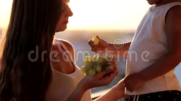 日落时分妈妈和她的小女儿在阳台上吃葡萄视频的预览图