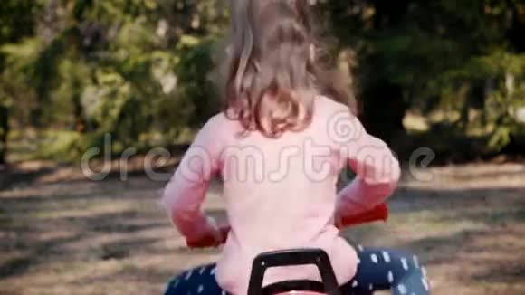 女孩骑在森林里的玩具四轮车上视频的预览图
