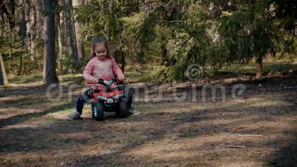 女孩骑在森林里的玩具四轮车上视频的预览图