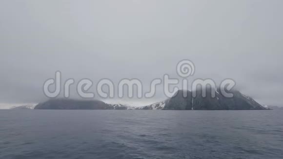 雪岛上的雾山和悬崖在冰冷的海水中来自帆船视频的预览图