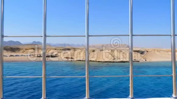 夏天大海透过甲板上的金属栅栏你可以看到一个美丽的海景荒芜的海岸帐篷和机器视频的预览图