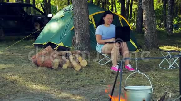 女人坐在帐篷附近用笔记本电脑工作视频的预览图