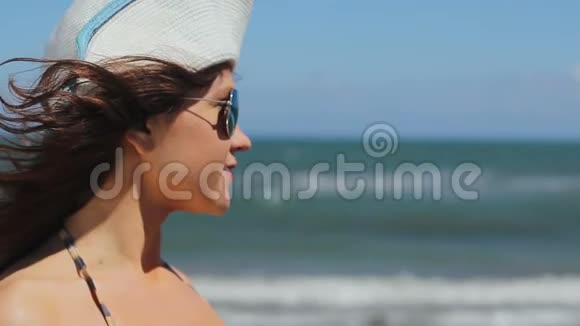 年轻女性戴着太阳镜在海边的阳光沙滩上尽情放松视频的预览图