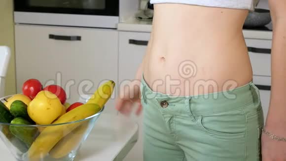 苗条的女人在一盘水果和蔬菜的背景下测量臀部这是一种健康的生活方式视频的预览图