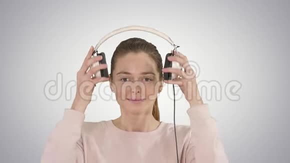 一位年轻女子在渐变背景下用耳机听音乐视频的预览图