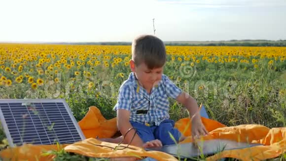 儿童使用太阳能电池充电笔记本电脑背景领域向日葵快乐的孩子看笔记本与太阳能视频的预览图