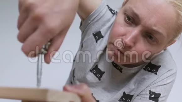 一个女人坐在地板上收集房间里的木制家具用螺丝刀拧螺丝视频的预览图