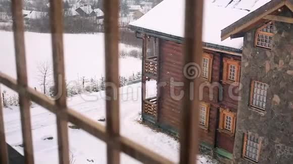 在大雪期间透过窗户观看山村的木屋落在木屋上的雪视频的预览图