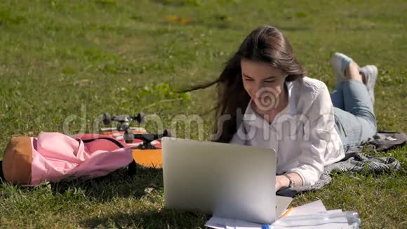 在大学校园公园用笔记本电脑工作的学生女孩的正面景色视频的预览图