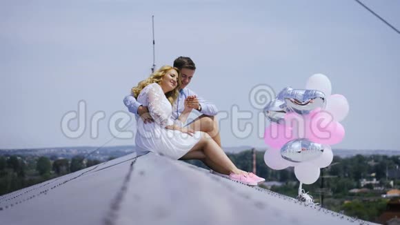 电影院年轻夫妇拿着气球坐在屋顶上视频的预览图
