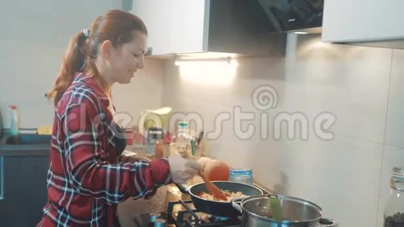 女孩做饭站在炉子旁在室内厨房里的格栅里煎站在火炉旁的女人视频的预览图