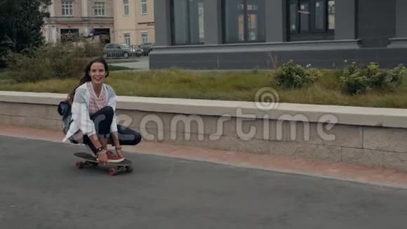 美丽的年轻女孩带着背包骑着长板在阳光明媚的天气滑板运动员滑板学生视频的预览图