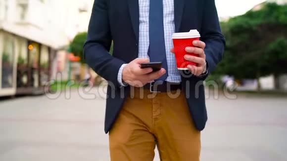 男人用智能手机喝着咖啡走在街上视频的预览图